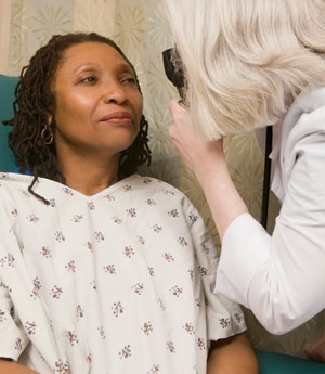 We offer emergency eye care in Okotoks. A doctor examines a woman's eye.