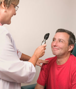 We offer eye exams for specific health conditions. A woman examines a man's eye.
